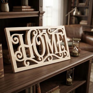 May include: A rectangular light-colored wooden sign featuring the word HOME cut out in a decorative, swirling script font. The sign is framed by a rectangular border and displays intricate, ornate scrollwork details integrated into the lettering.