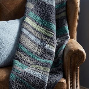 Close-up texture of hand-quilted stipple stitching on modern patchwork quilt