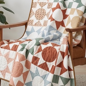 May include: A patchwork quilt featuring a repeating geometric pattern of stars and circles in muted tones of terracotta, sage green, dusty blue, and cream. The fabric displays various small-scale floral and dotted prints, with visible stitching.
