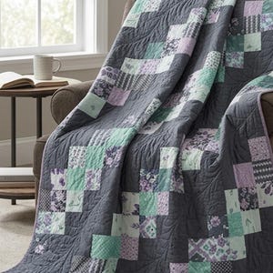 May include: A patchwork quilt featuring a repeating pattern of dark gray, light mint green, and soft lavender squares. The fabric squares display various floral and geometric prints, all unified by an overall swirling quilted texture.