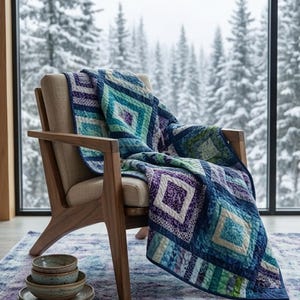May include: A quilt featuring a geometric diamond pattern in shades of blue, teal, purple, and white draped over a wooden armchair with beige upholstery. A stack of three ceramic bowls sits on a patterned rug in the foreground.
