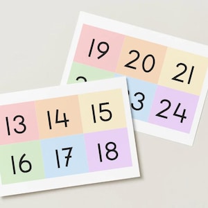 May include: Two rectangular cards featuring a grid of pastel-colored squares, each containing a black number. The front card displays numbers 13 through 18, while the partially visible card behind it shows numbers 19 through 24 in a similar grid layout.