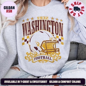 May include: A light gray crewneck sweatshirt featuring a graphic print with the text 1932 WASHINGTON FOOTBALL. The design includes a football helmet, a checkered pattern, and stars in maroon and gold colors, centered on the front of the garment.