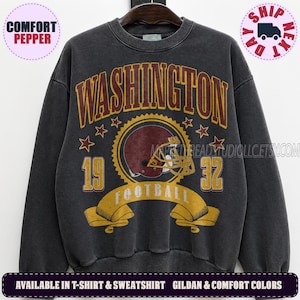 May include: A charcoal grey crewneck sweatshirt featuring a vintage-style graphic with the text WASHINGTON in arched maroon letters, the number 1932, a football helmet illustration, and a yellow banner with the word FOOTBALL printed across the front.
