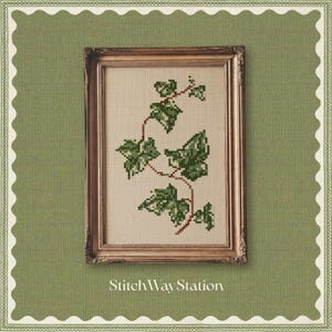May include: A framed cross-stitch embroidery featuring a trailing ivy vine with variegated green leaves on a light beige fabric background. The artwork is encased in a rectangular, ornate metallic gold frame with intricate detailing.