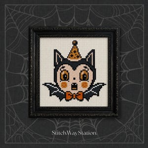 May include: A cross-stitch embroidery in a black frame featuring a stylised bat character with large orange eyes, a party hat, and an orange bowtie. The character has black wings and a cream-coloured face. The text StitchWayStation is at the bottom.