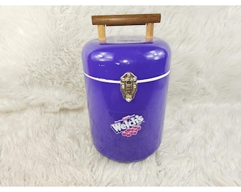 Enfriador cilíndrico morado de refresco de uva espumoso Welch's con asa de madera grabada.