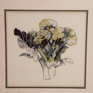 May include: A framed cross-stitch embroidery depicting a bouquet of yellow flowers with green leaves and a brown stem.