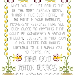 May include: A cross-stitch design on white fabric featuring a quote with decorative floral and geometric borders. The text reads, "WHAT YOU'VE JUST SAID IS ONE...MAY GOD HAVE MERCY ON YOUR SOUL."