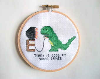 T-Rex is good at video games, completed cross stitch with T-Rex playing on an old TV, in 4 in. natural wood embroidery hoop