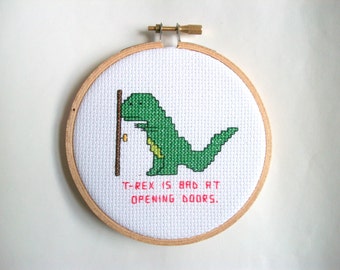 T-Rex is bad at opening doors, completed cross stitch with T-Rex unable to reach the doorknob, in 4 in. natural wood embroidery hoop