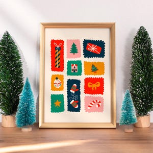 May include: A framed art print featuring a grid of colorful, scalloped-edge rectangular illustrations. The designs include a tall gift, a pine tree, a red present, a house, a small tree, an ornament, mittens, a bow, a star, and a candy cane.