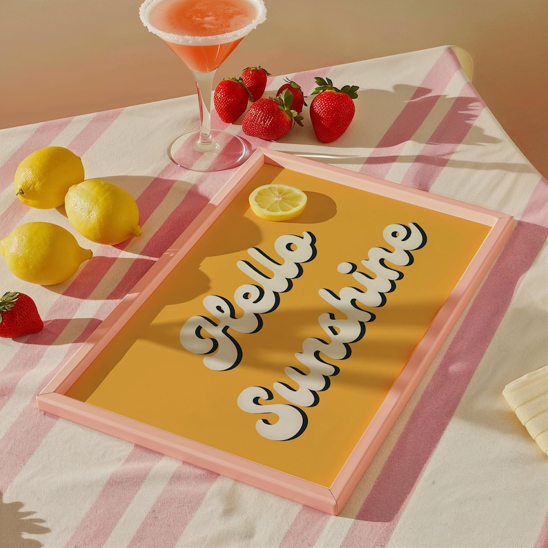 May include: A pink framed tray with a yellow background and the text "Hello Sunshine" in white. The tray is on a pink and white striped surface with lemons and strawberries.