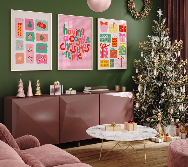 May include: Three framed wall art prints featuring colorful holiday illustrations and the text "having a cosy christmas time" in red and green. The prints are displayed above a dark mauve sideboard with decorative items and a Christmas tree.