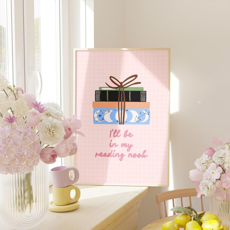 May include: A pink and white printable wall art print with a stack of books tied with a brown ribbon. The text on the print reads "I'll be in my reading nook".