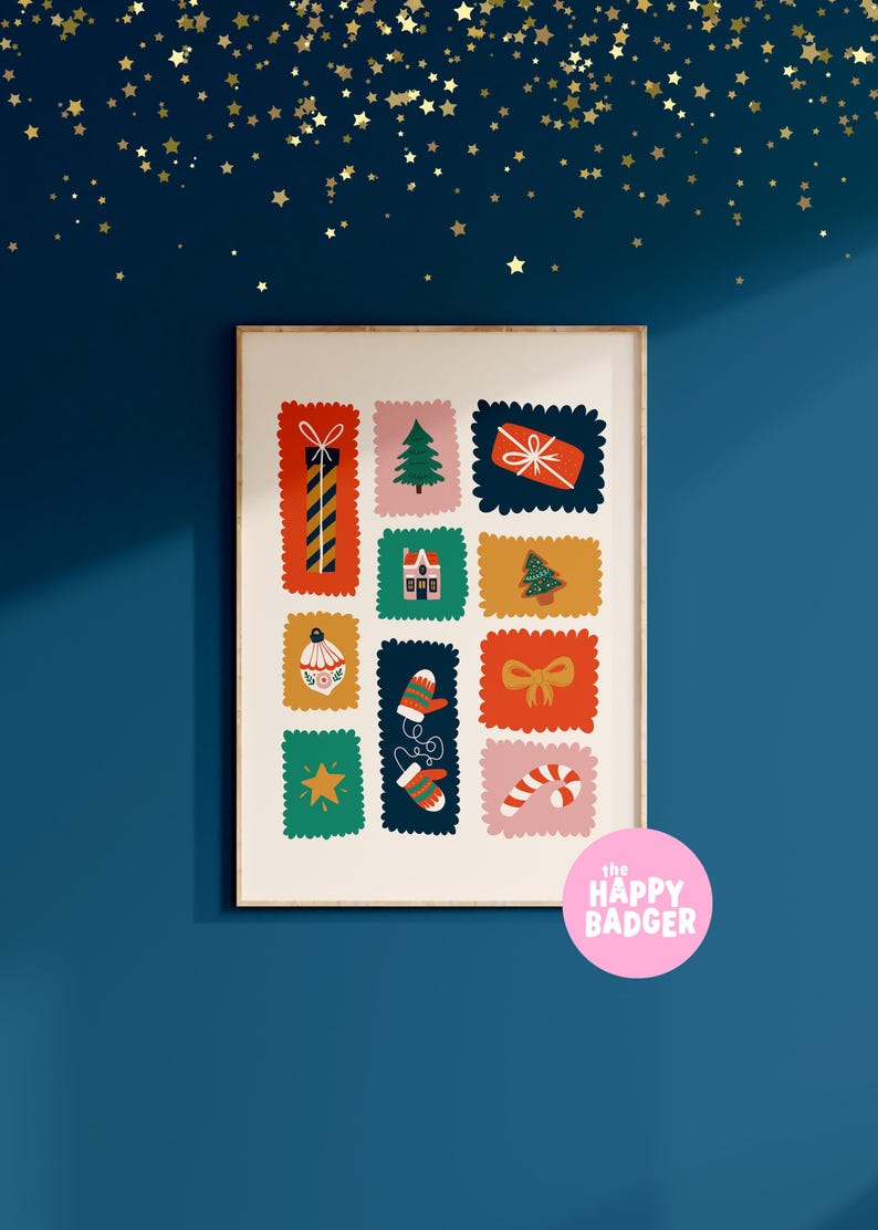 May include: A rectangular wall art print in a light wooden frame featuring a grid of twelve colorful postage stamp-style illustrations of Christmas icons including a gift, tree, house, ornament, mittens, bow, star, and candy cane with a pink logo.