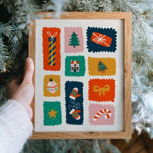May include: A framed print featuring a grid of colorful, scalloped-edge rectangles containing holiday illustrations: a striped gift, a pine tree, a wrapped present, a house, a gingerbread tree, an ornament, mittens, a bow, a star, and a candy cane.