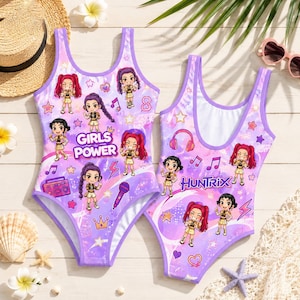 May include: Two one-piece swimsuits featuring a purple and white gradient background with cartoon characters, musical notes, stars, hearts, and lightning bolts. The text GIRLS POWER and HUNTRIX are printed on the front of the swimsuits.