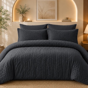 May include: A dark charcoal gray bedding set featuring a textured, vertically striped quilt cover and two matching rectangular pillow shams. The bedding has a consistent, uniform dark gray color and a subtle, tactile ribbed surface pattern.