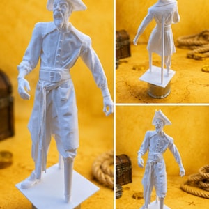 May include: A white 3D printed figurine of a pirate wearing a tricorn hat, a long coat, and a sash, featuring a peg leg and standing on a square base. The figure is depicted from three different angles, showing the front, back, and side profile.