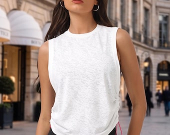 Pode incluir: Uma regata branca sem mangas com tecido texturizado semitransparente, decote redondo e detalhe de cordão lateral com um fio fino em rosa brilhante. A peça é combinada com leggings pretas lisas, criando um visual simples e funcional.