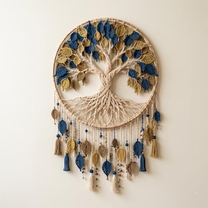 Puede incluir: Un tapiz circular de macramé con un diseño de árbol de la vida, con ramas tejidas en color beige y un follaje de hojas azul oscuro y amarillo mostaza. Incluye cordones colgantes decorados con motivos de hojas, borlas y cuentas.