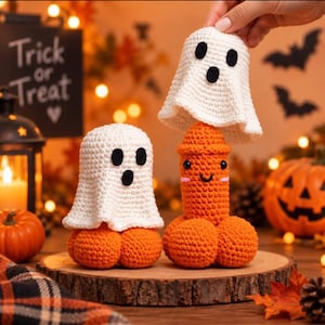 May include: Two crocheted figures featuring orange phallic-shaped bases with round tops and white ghost covers. Each ghost has two black oval eyes and a small black oval mouth. The orange figures have small black eyes and a stitched smile.