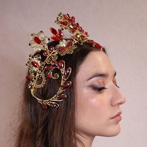 Peut inclure: Un diadème de tête en or et rouge orné de bijoux avec un motif floral. La couronne est en métal et présente un design délicat et complexe. Le bandeau est orné de bijoux rouges et d'accents dorés.