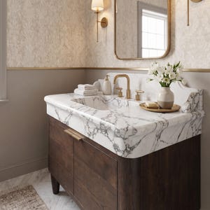 Angled view of a custom Calacatta marble bathroom vanity with an integrated sink, dramatic white marble, bold gray veining, brushed brass hardware, and a handcrafted dark oak cabinet. Elegant natural stone vanity for luxury bathroom designs.