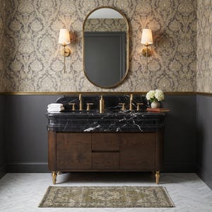 Elegant master bathroom featuring a custom Nero Marquina double vanity with integrated marble sinks, sculpted countertop, brushed brass faucets, dark walnut cabinetry, designer wallpaper, oval mirror, brass sconces, and premium natural black marble highlighted by striking white veining throughout the surface.