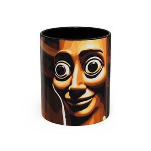 Peut inclure: Un mug cylindrique en céramique avec un intérieur et un bord noirs. L'extérieur présente une illustration graphique stylisée à fort contraste d'un visage aux yeux larges et saillants et au sourire subtil, dans des tons orange, marron et noir.