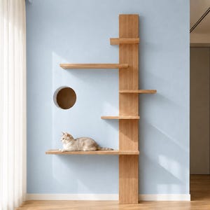 以下が含まれることがあります： 明るい色の木材で作られた壁掛け式のキャットタワー。垂直な中央支柱に長さの異なる5つの水平な棚板と左側に円形の開口部があり、一番下の棚には明るい色の猫が横たわっています。
