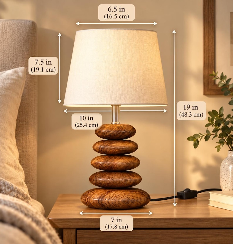 Puede incluir: Una l&aacute;mpara de mesa con pantalla de tela beige y base compuesta por cinco piedras apiladas con veteado de madera pulida. La l&aacute;mpara mide 48,3 cm de alto, con un di&aacute;metro superior de 16,5 cm, inferior de 25,4 cm y 17,8 cm de ancho de base.