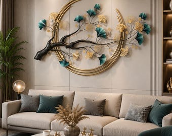 Puede incluir: Una gran escultura de pared de metal que presenta una rama de árbol oscura y texturizada que se extiende sobre un marco circular dorado. La rama está adornada con numerosas hojas de ginkgo delicadas en tonos verde azulado y oro.