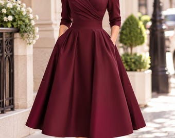 Può includere: Un abito midi color bordeaux intenso caratterizzato da un ampio collo a scialle, maniche a tre quarti e un corpetto aderente con dettagli a portafoglio. La gonna è ampia e plissettata, cade sotto le ginocchia e include tasche laterali.