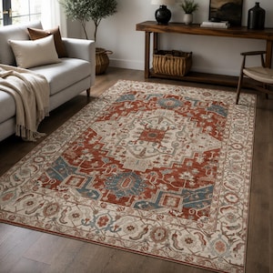 May include: A rectangular area rug featuring a central medallion design with a palette of rust orange, muted blue, and cream. The rug displays intricate geometric and floral patterns throughout the field and a wide, detailed border.