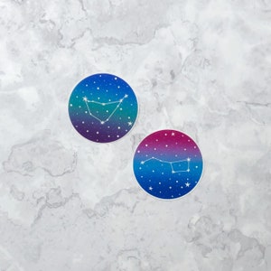 May include: Two round stickers with a galaxy background and white constellation outlines. The top sticker features the constellation Capricorn, while the bottom sticker features the constellation Ursa Major.