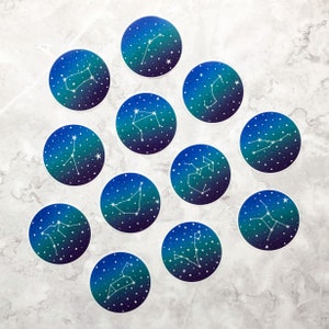 May include: Twelve round stickers with a blue background and white constellations. Each sticker features a different constellation with its name.