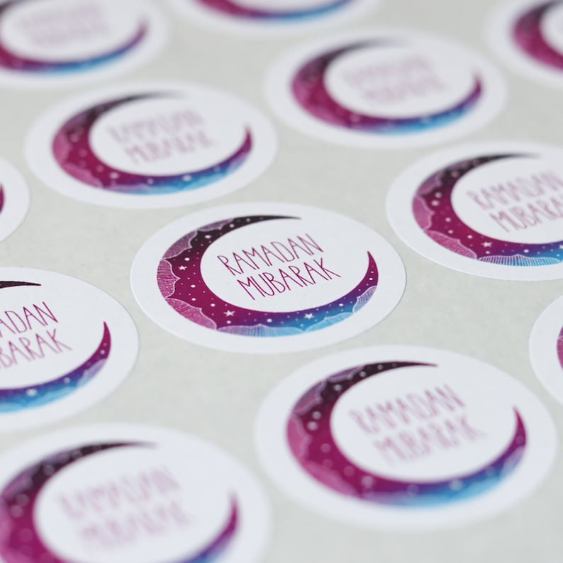 May include: A set of round stickers with a crescent moon design. The moon is a gradient of purple and blue with white stars. The text "Ramadan Mubarak" is written in a white cursive font.