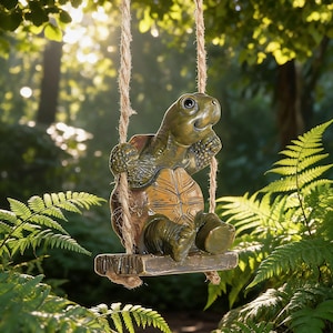 May include: A green and brown turtle figurine sitting on a small rectangular wooden swing suspended by two thick jute ropes. The turtle has a textured shell, detailed limbs, and a smooth head, positioned as if relaxing while hanging from the ropes.