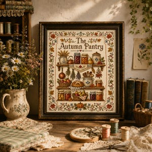 Può includere: Un ricamo a punto croce incorniciato intitolato The Autumn Pantry, che mostra scaffali pieni di barattoli, prodotti e utensili da cucina, circondato da un bordo decorativo di foglie autunnali, in una cornice di legno scuro.
