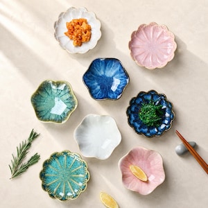 Puede incluir: Una colección de ocho platos pequeños de cerámica en varias formas y colores, incluyendo azul, verde, rosa y blanco. Algunos platos presentan un acabado de esmalte agrietado y bordes festoneados, mientras que otros son lisos.