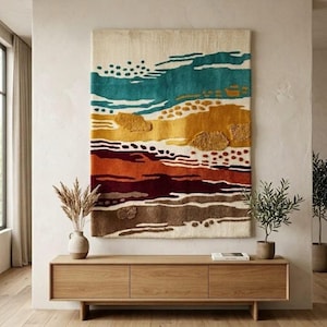 May include: A rectangular wall hanging featuring a textured, tufted design with horizontal bands of cream, teal, mustard yellow, burnt orange, and deep maroon. The composition includes abstract shapes, dots, and lines in a layered, multi-dimensional fiber art style.