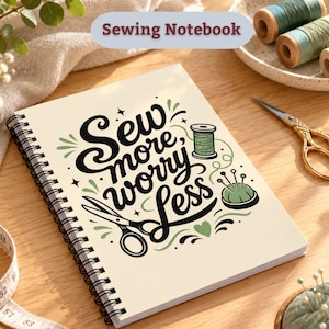 May include: A spiral-bound notebook with a cream-coloured cover featuring the black text "Sew more, worry less" alongside green illustrations of a spool of thread, a pincushion, and scissors. The design includes small stars and heart accents.