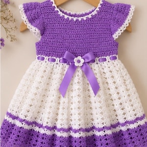 May include: A crochet dress featuring a purple bodice with short ruffled sleeves and a white skirt with a purple hem. The waist is accented with a purple satin ribbon threaded through the crochet and a central purple bow with a small white flower.