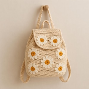 Può includere: Uno zaino all'uncinetto color beige con un motivo di margherite bianche e gialle. La borsa presenta una chiusura a patta con due margherite, un corpo principale con quattro margherite e due spallacci. La struttura è interamente in filato.