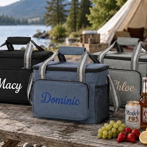 Könnte beinhalten: Drei rechteckige Kühltaschen in Schwarz, Blau und Grau, jeweils mit Tragegriff, Schultergurt und einer Vordertasche, die mit den Namen Macy, Dominic und Chloe bestickt ist. Die Taschen stehen auf einer hölzernen Oberfläche.
