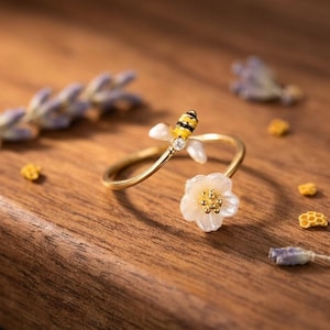 Anel vazado com flor e abelha em prata de lei S925, joia floral ajustável inspirada na natureza.