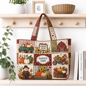 May include: A quilted tote bag featuring a patchwork design with autumn-themed illustrations including a green truck with pumpkins, a red barn, a scarecrow, sunflowers, and baskets of gourds. The center panel displays the text Harvest Farm.