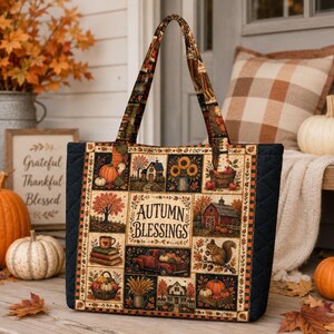 May include: A quilted tote bag featuring a patchwork design with autumn-themed illustrations including pumpkins, a red truck, a barn, sunflowers, and a squirrel. The center panel displays the text Autumn Blessings in a dark brown font.